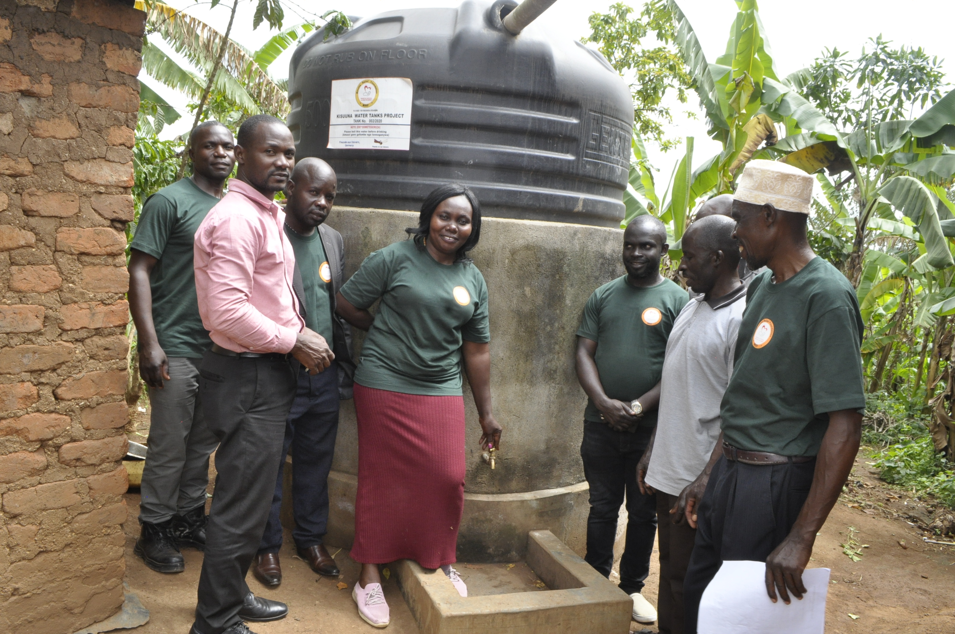 Community gathering at water tank installation site in Namagembe