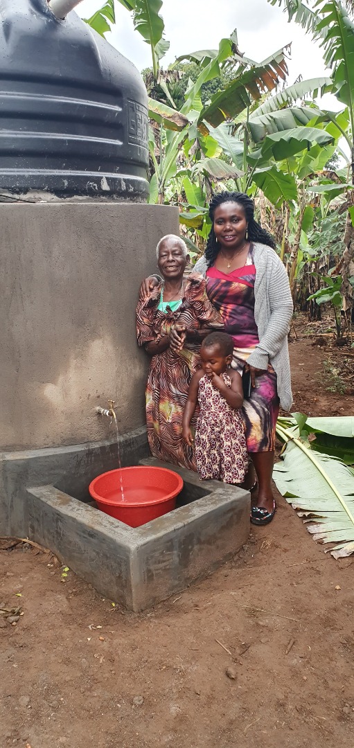 Mukadde Namagembe standing next to her new water tank from MRF